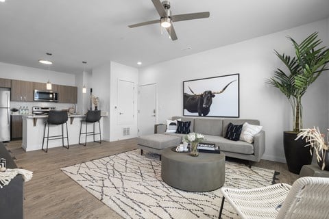 A modern living room with a grey couch, a coffee table, and a painting of a bull on the wall.